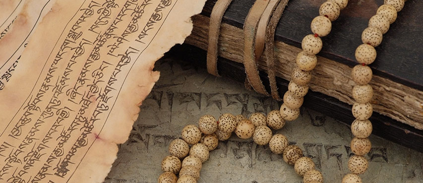 A traditional Tibetan Buddhist book, and a mala – beads used to count mantras during meditation